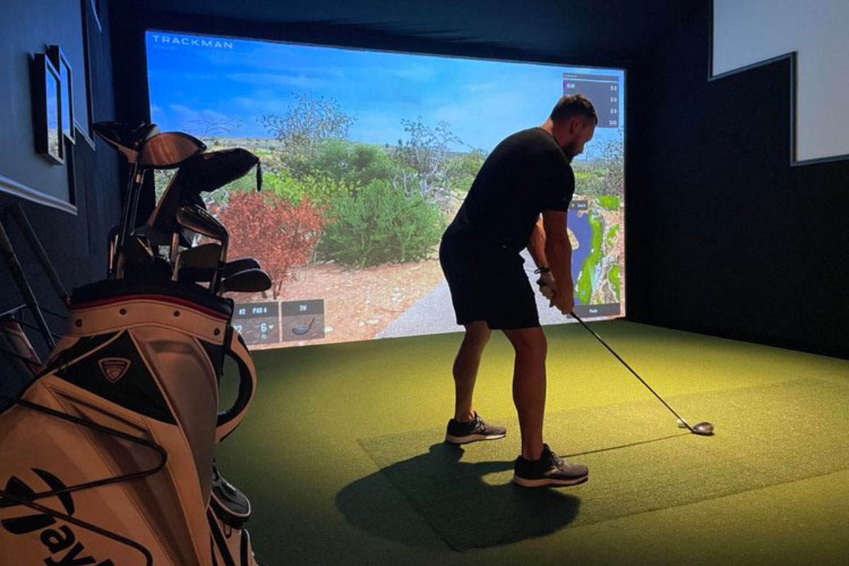 Man at indoor golf bay readies his swing