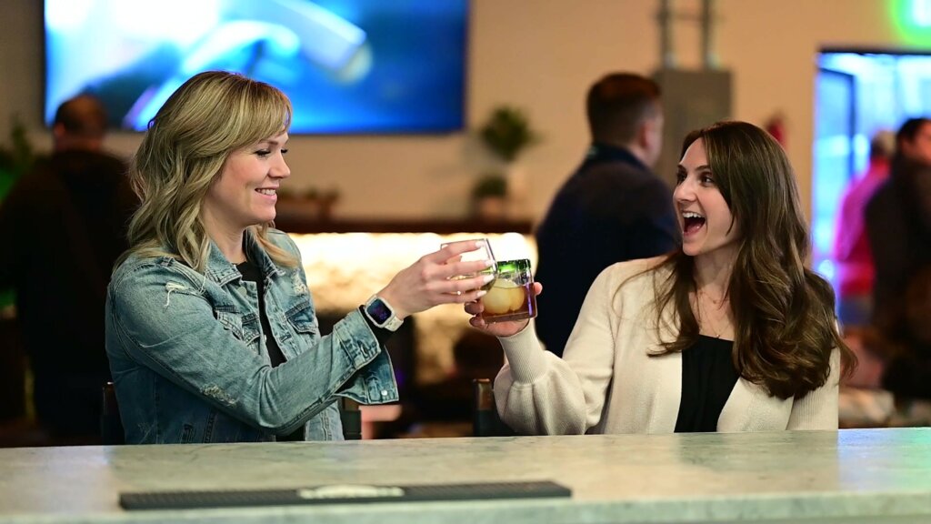 Two smiling women toast to each other at the bar